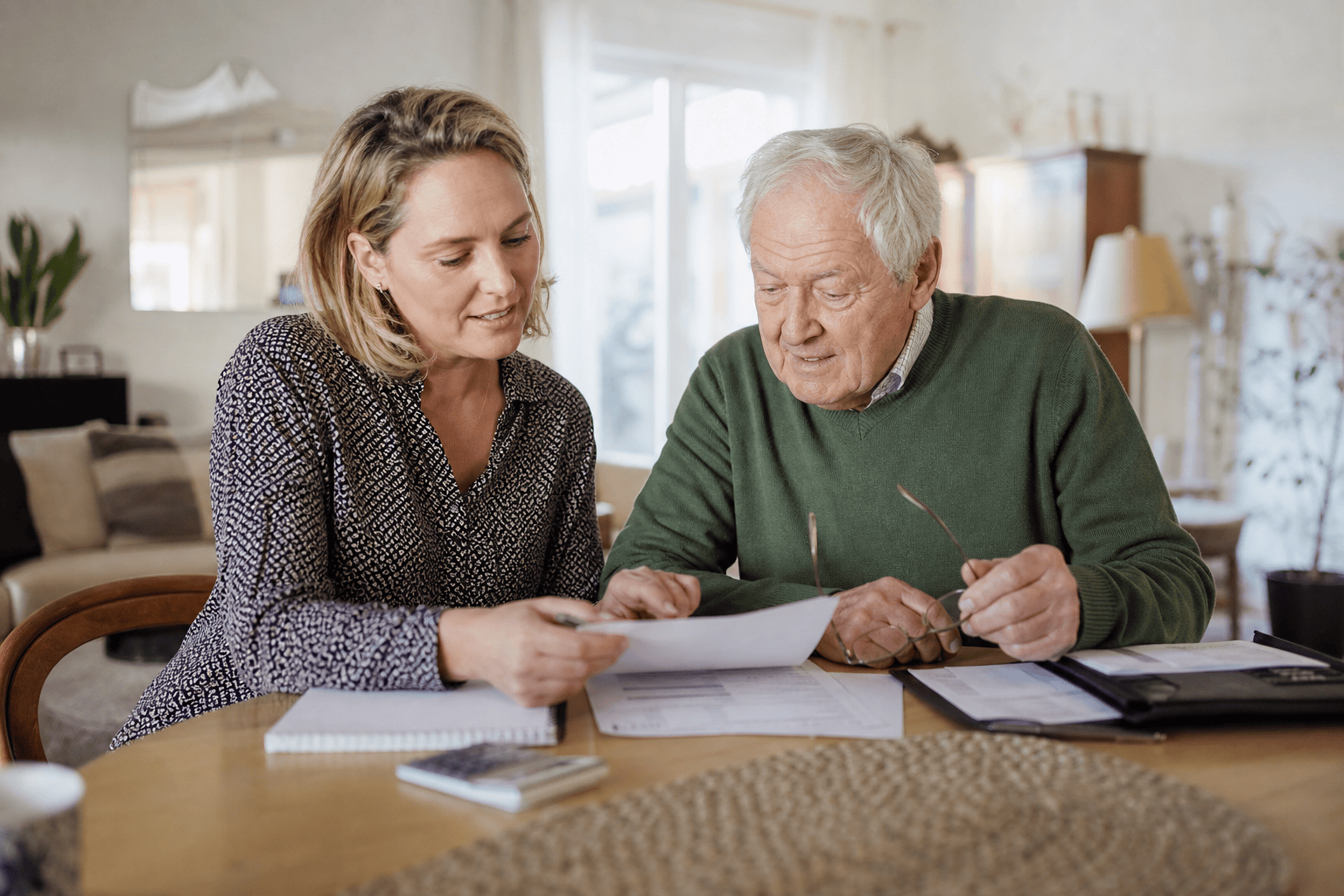 Angehörige und älterer Mann besprechen eine Übersicht zu Pflege- und Betreuungskosten
