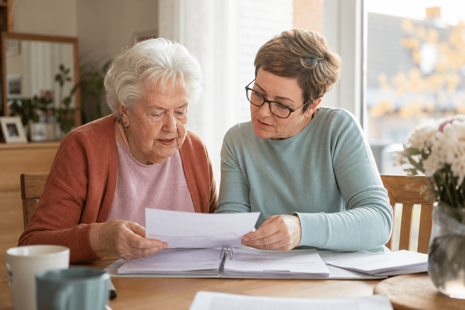 Ältere Person und Angehöriger besprechen eine Checkliste am Esstisch
