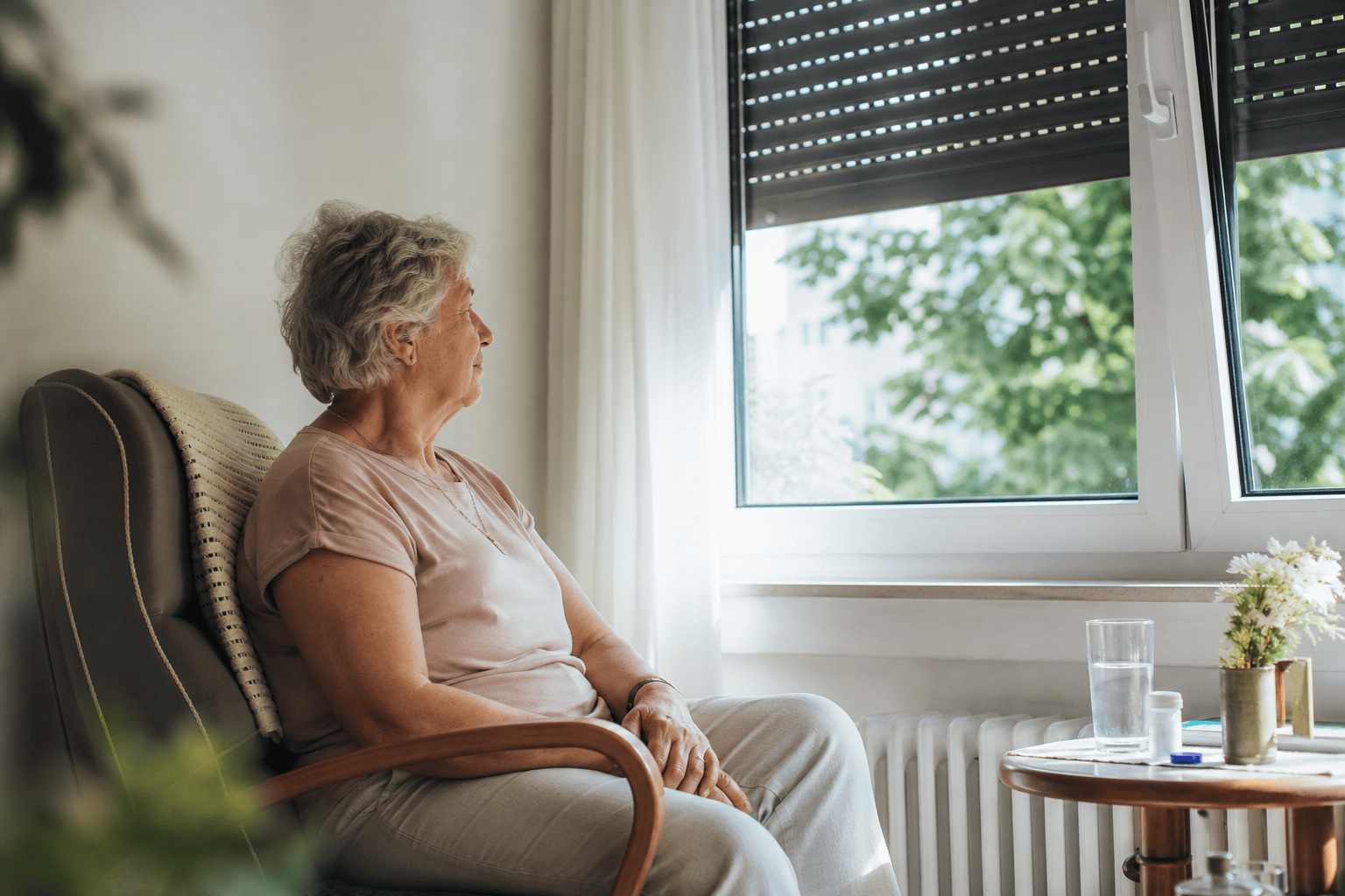 Ältere Person ruht in einem hellen, vor Sonne geschützten Wohnraum.