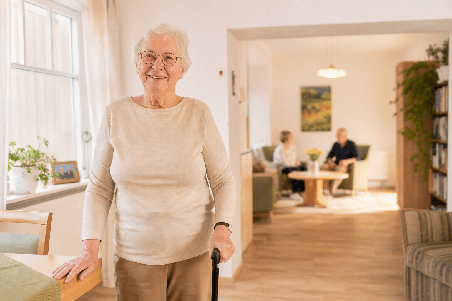 Ältere Person in einem hellen, barrierearmen Wohnbereich mit Gemeinschaftsangebot.